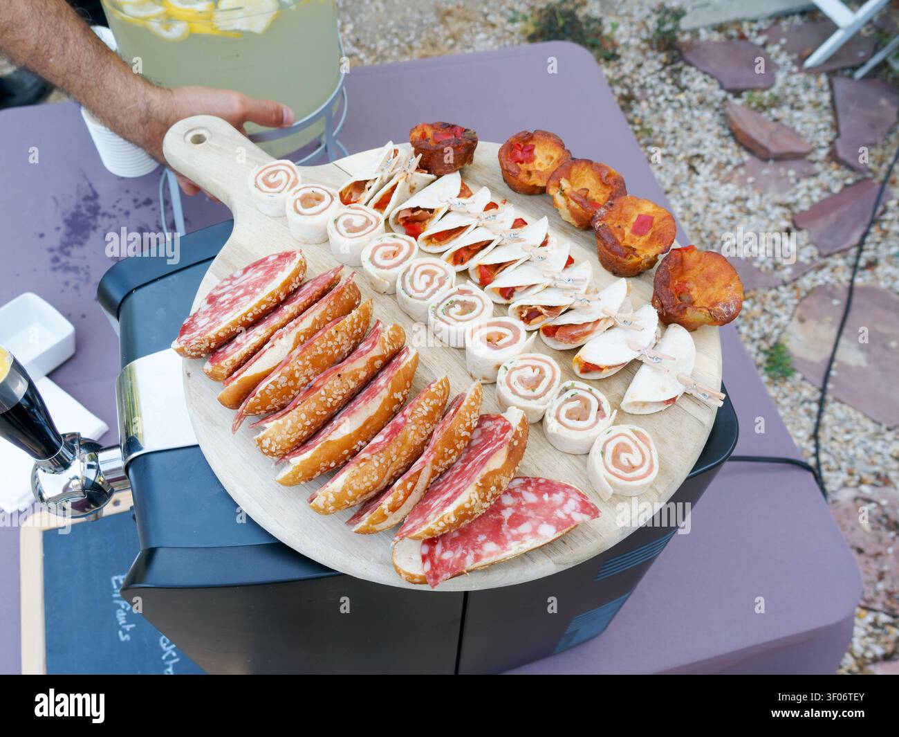Assortiti canapé salati con carni affumicate, involtini e mini pizze su un vassoio di servizio in legno Foto Stock