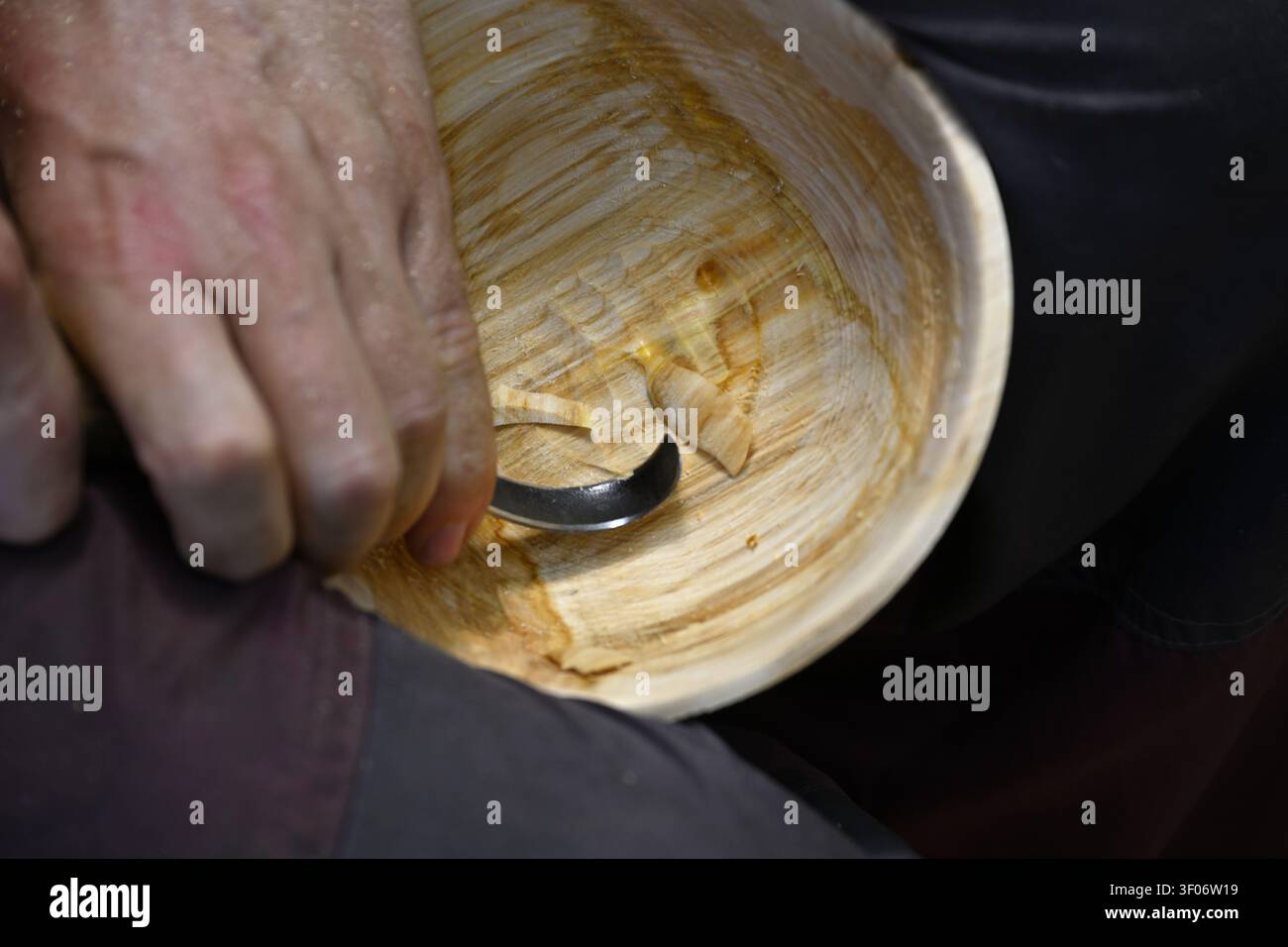 Artigiano che utilizza un coltello a gancio per intagliare a cucchiaio per pulire l'interno della ciotola di legno tornita su tornio Foto Stock
