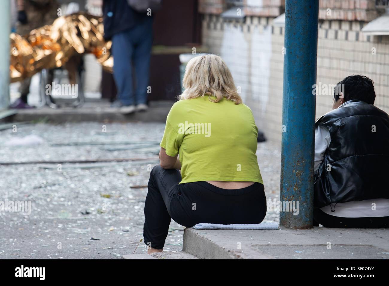 Persone disperate sedute tra le macerie dopo una devastante catastrofe urbana Foto Stock