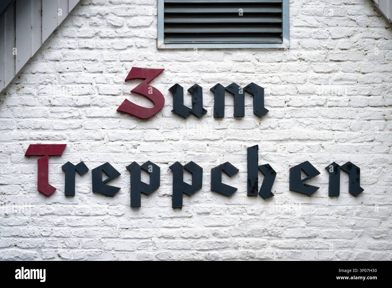 Colonia, Germania, 04 luglio 2026: Insegna tradizionale in caratteri gotici della famosa taverna storica Zum Treppchen su un muro di mattoni dipinto di bianco a Colonia Roden Foto Stock