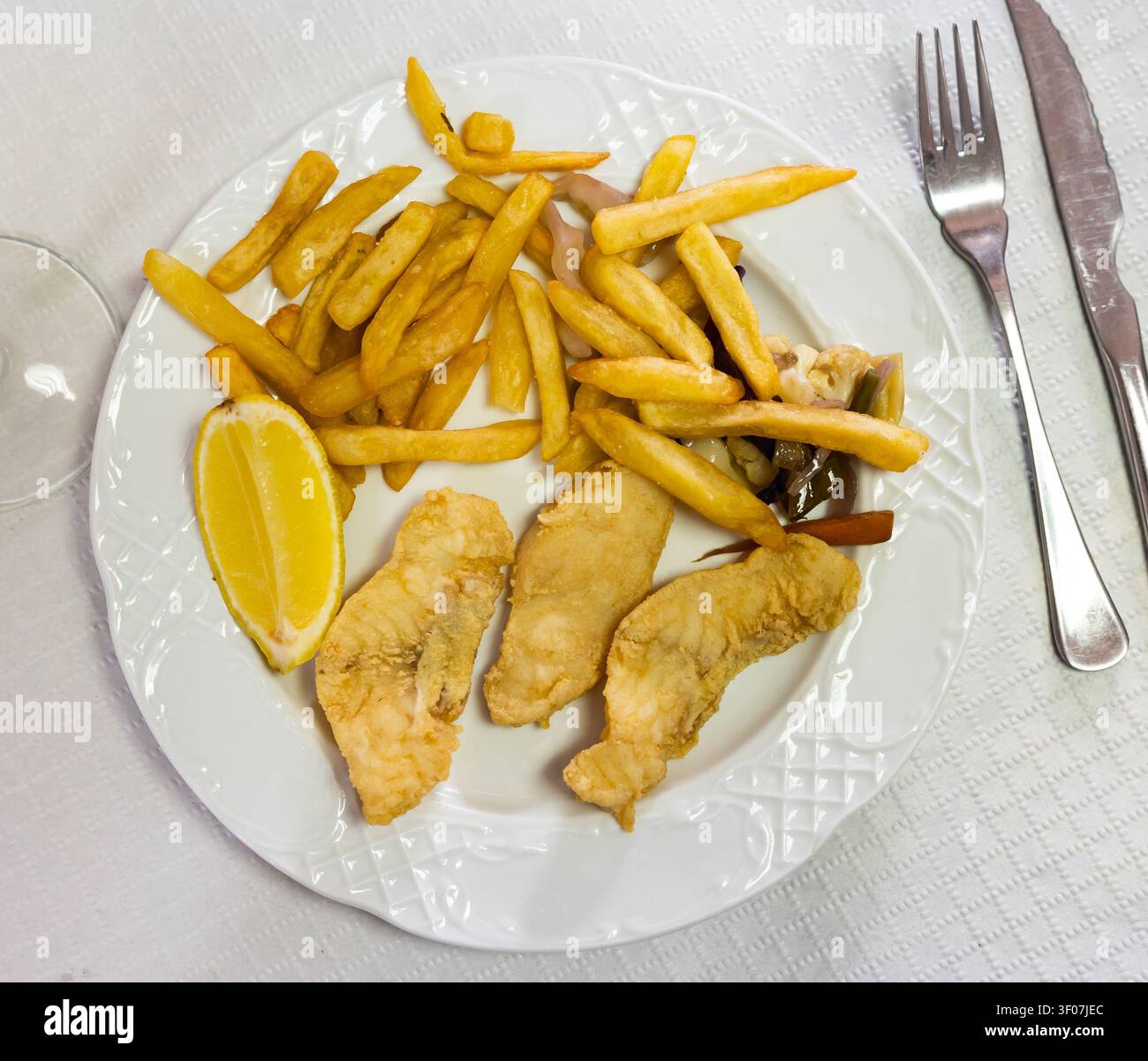 Pesce in pastella con limone e patate Foto Stock
