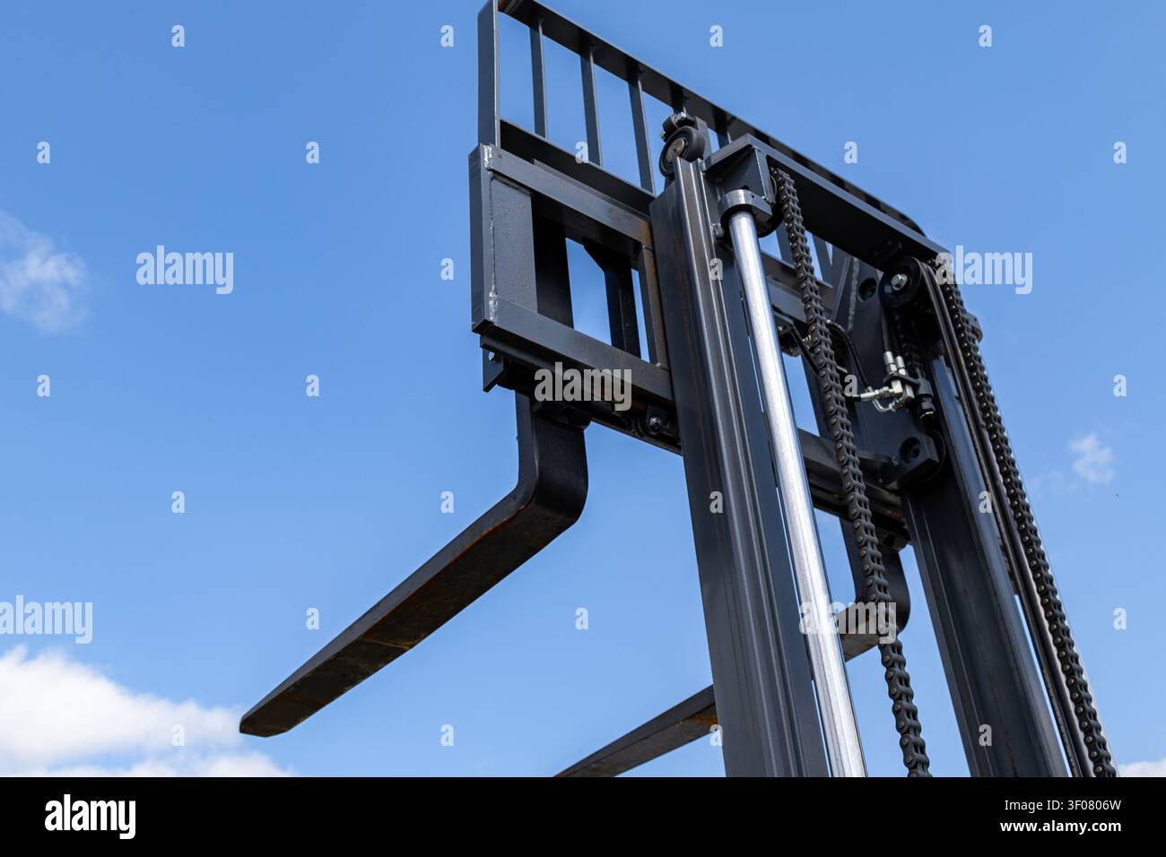 Asto di carrello elevatore con una singola forca metallica estesa verso l'alto. Rail verticali, catene e componenti idraulici formano l'assieme di sollevamento Foto Stock