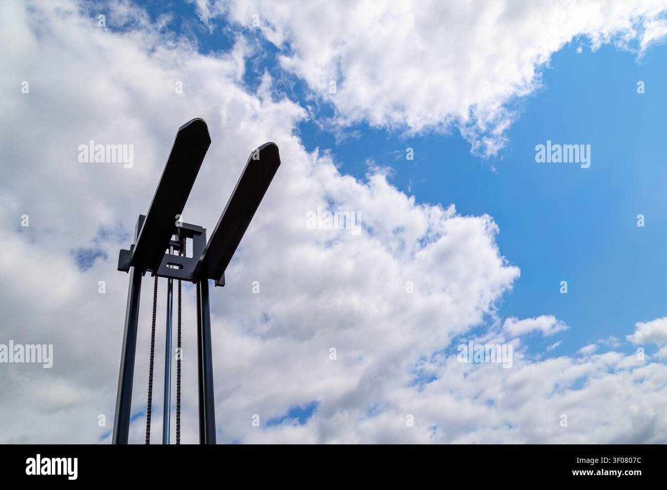 Asta di carrello elevatore con forche metalliche estese verso l'alto. Binari verticali, catene ed elementi strutturali formano la sezione di sollevamento. Foto Stock