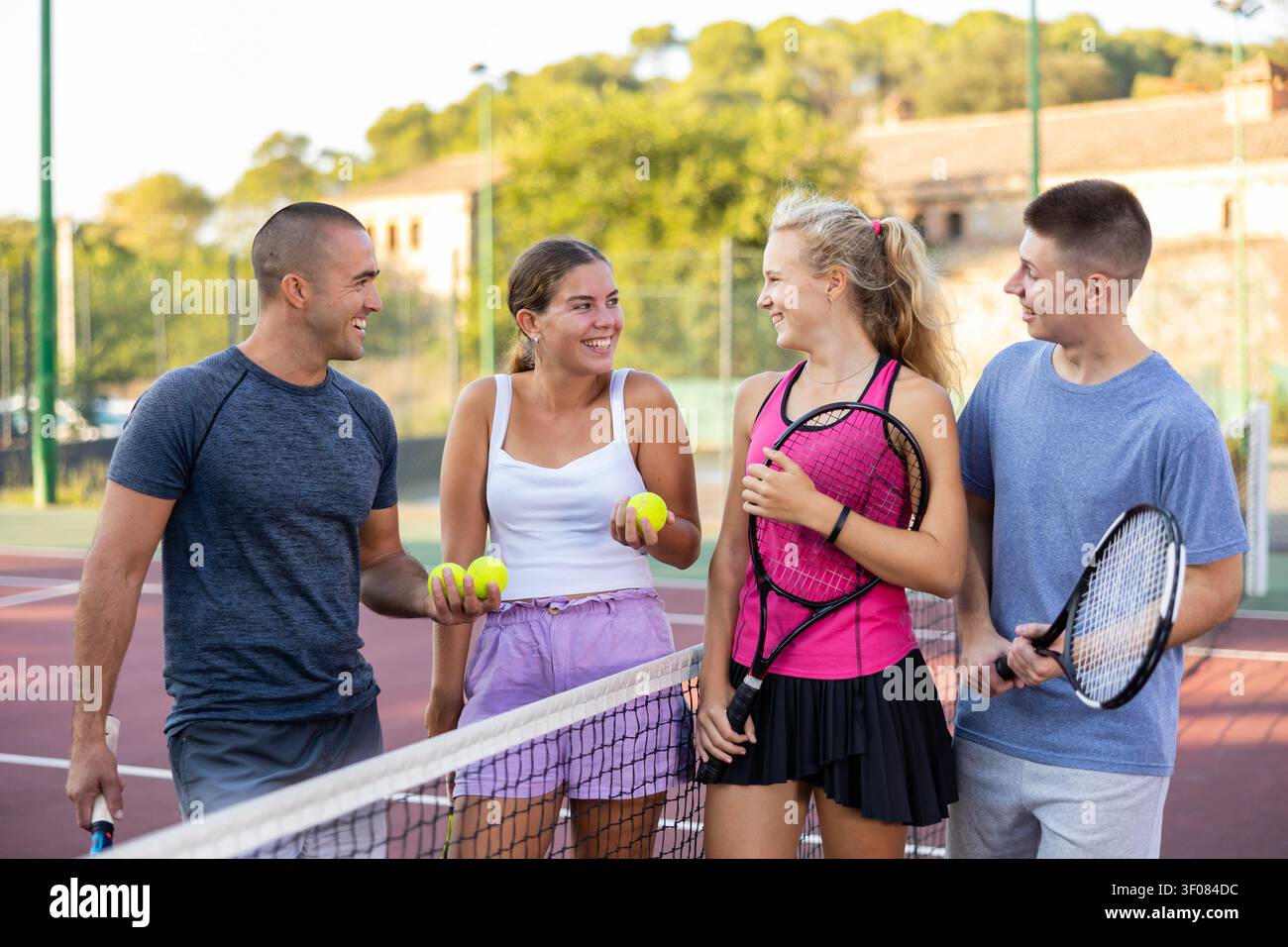 Uomini e donne che hanno conversazione sul campo da tennis all'aperto Foto Stock