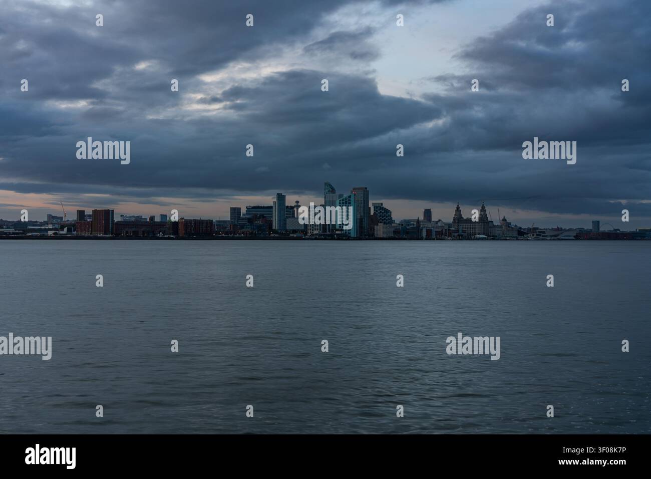 Silhouette di Liverpool illuminata al crepuscolo sotto pesanti nuvole temporalesche sul fiume Mersey Foto Stock