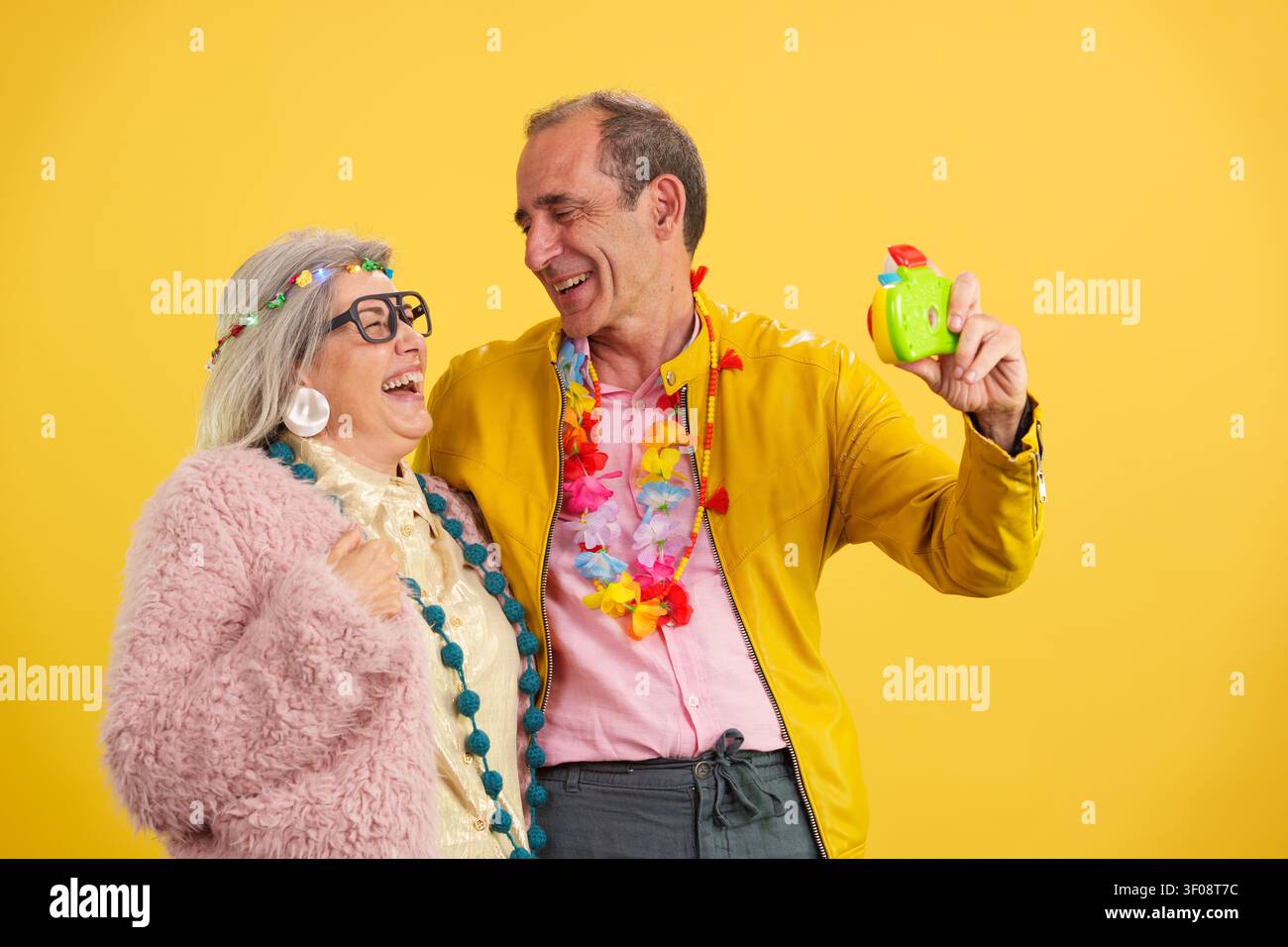 Coppia matura attiva che ride e celebra con una macchina fotografica giocattolo Foto Stock