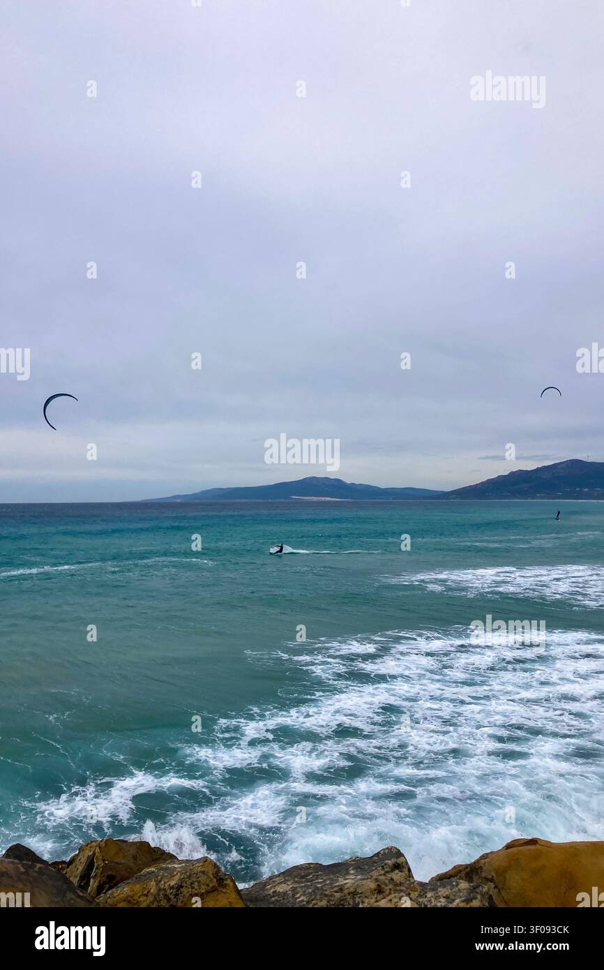 TARIFA, SPAGNA - 2 GENNAIO 2026: Un windsurfista cavalca forti venti atlantici al largo di Tarifa, in Spagna, catturando velocità, libertà ed energia costiera. - Immagine stock catturata con smartphone