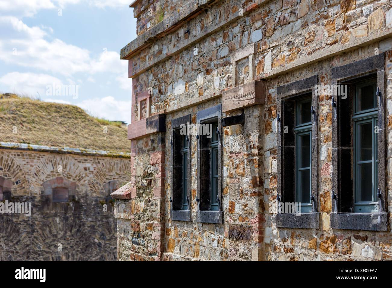 Facciata in pietra di una fortezza storica con finestre restaurate e mura in muratura medievale Foto Stock