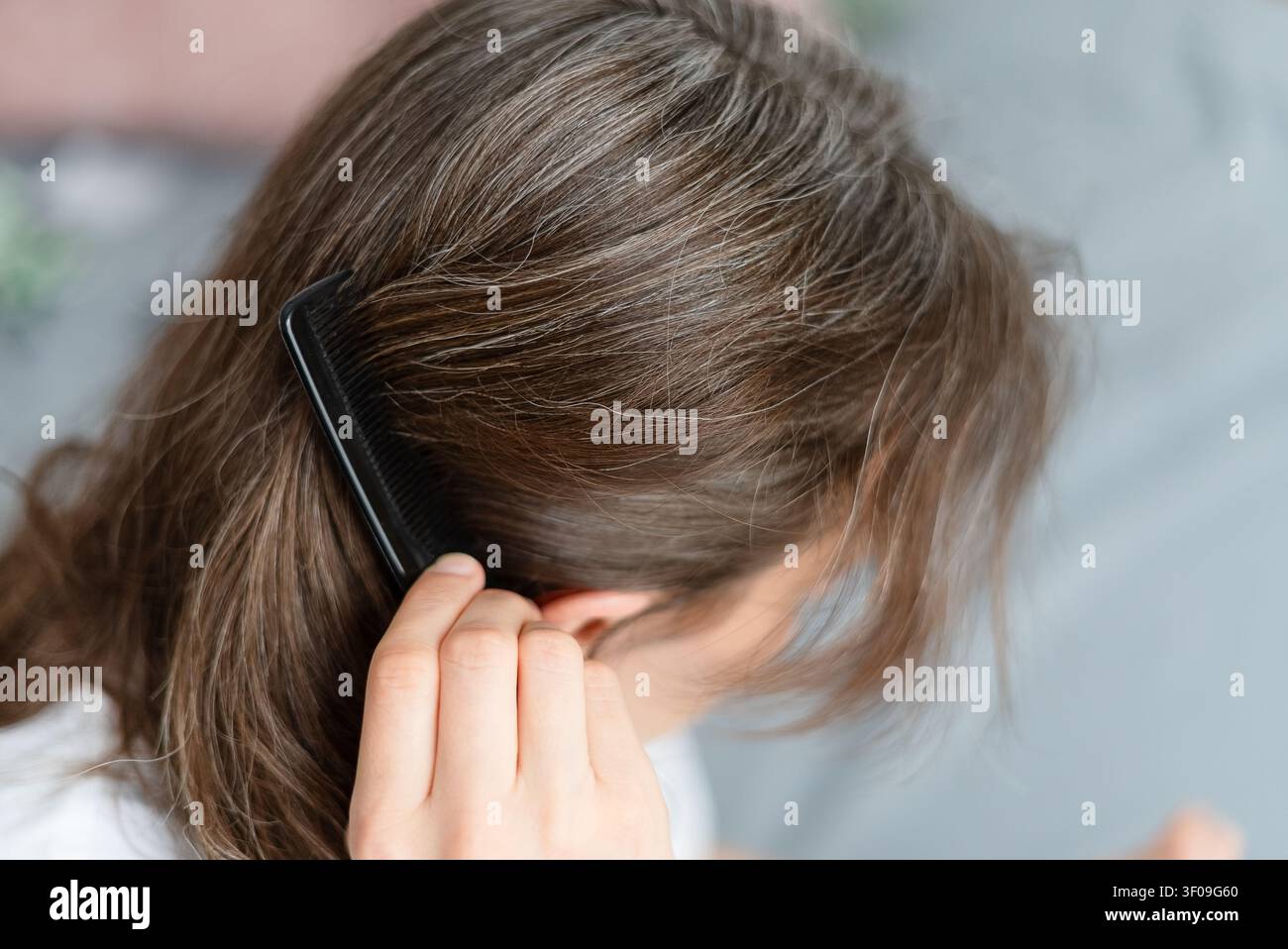 Donna vede come i disturbi legati alla malattia hanno influenzato i suoi capelli ingrigiti. Adulta matura riporta le ciocche argentate a una malattia e un trattamento passati. Madre accetta questo cambiamento come parte del percorso di salute. Foto Stock
