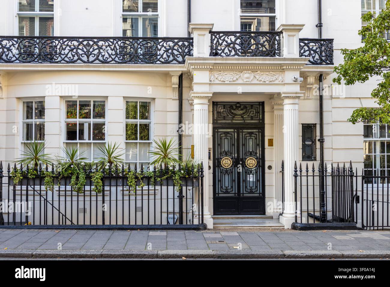 Esterno di una tradizionale casa di città britannica con elegante portico e ringhiere nere Foto Stock