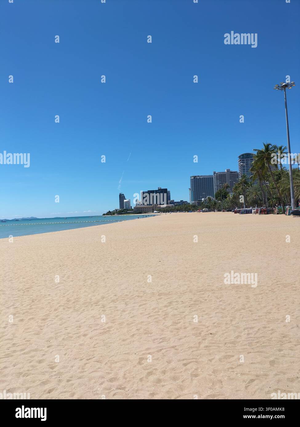 Vista grandangolare di una splendida spiaggia di sabbia e dello skyline della città sotto un cielo blu limpido a Pattaya, Thailandia. - Immagine stock catturata con smartphone