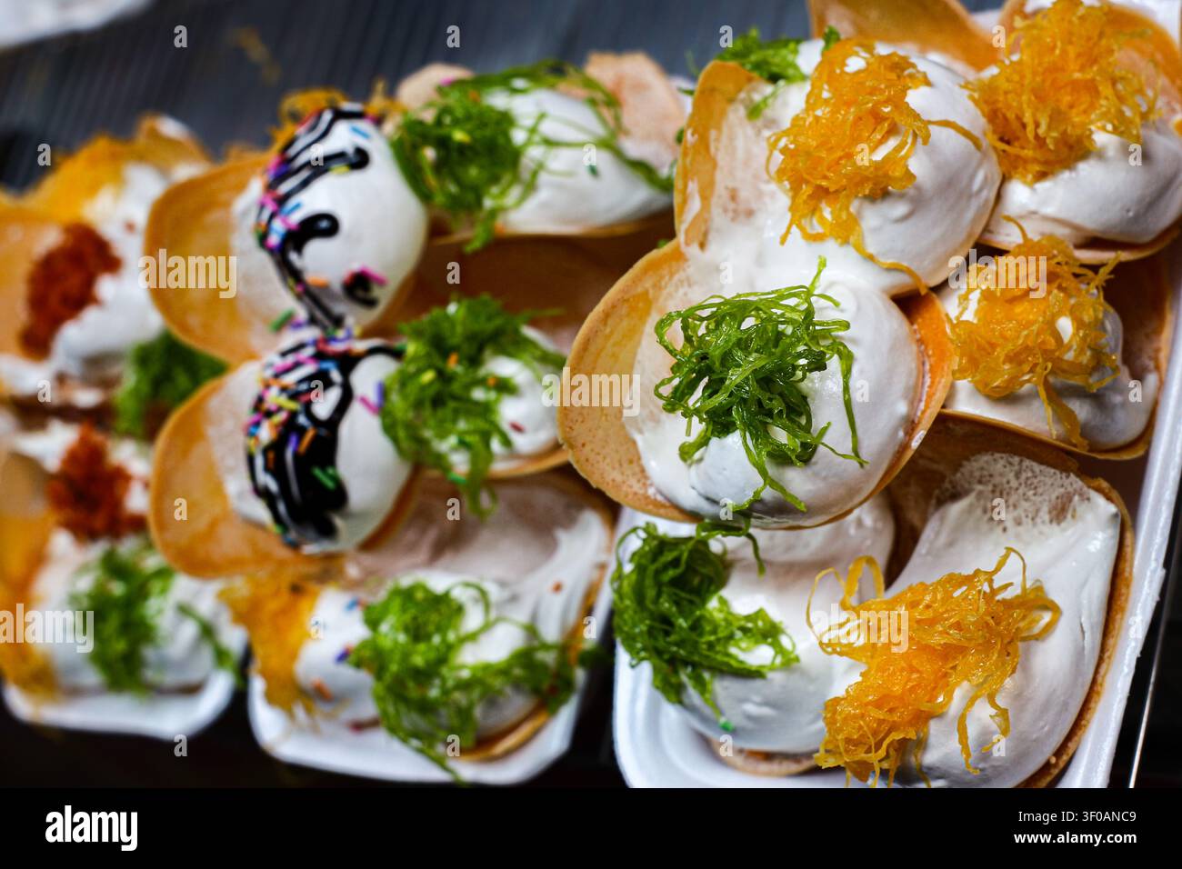 Close up di crepe thailandesi croccanti con panna montata, foi thong, guarnizione di pandan, salsa al cioccolato e ripieni di dessert colorati. Foto Stock