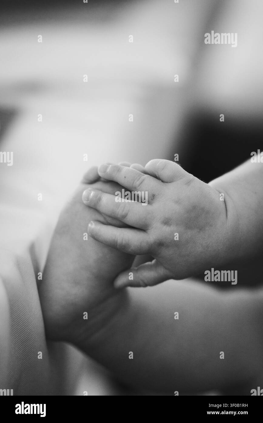 Close-up artistico in bianco e nero di una mano da bambino che tiene un piede Foto Stock