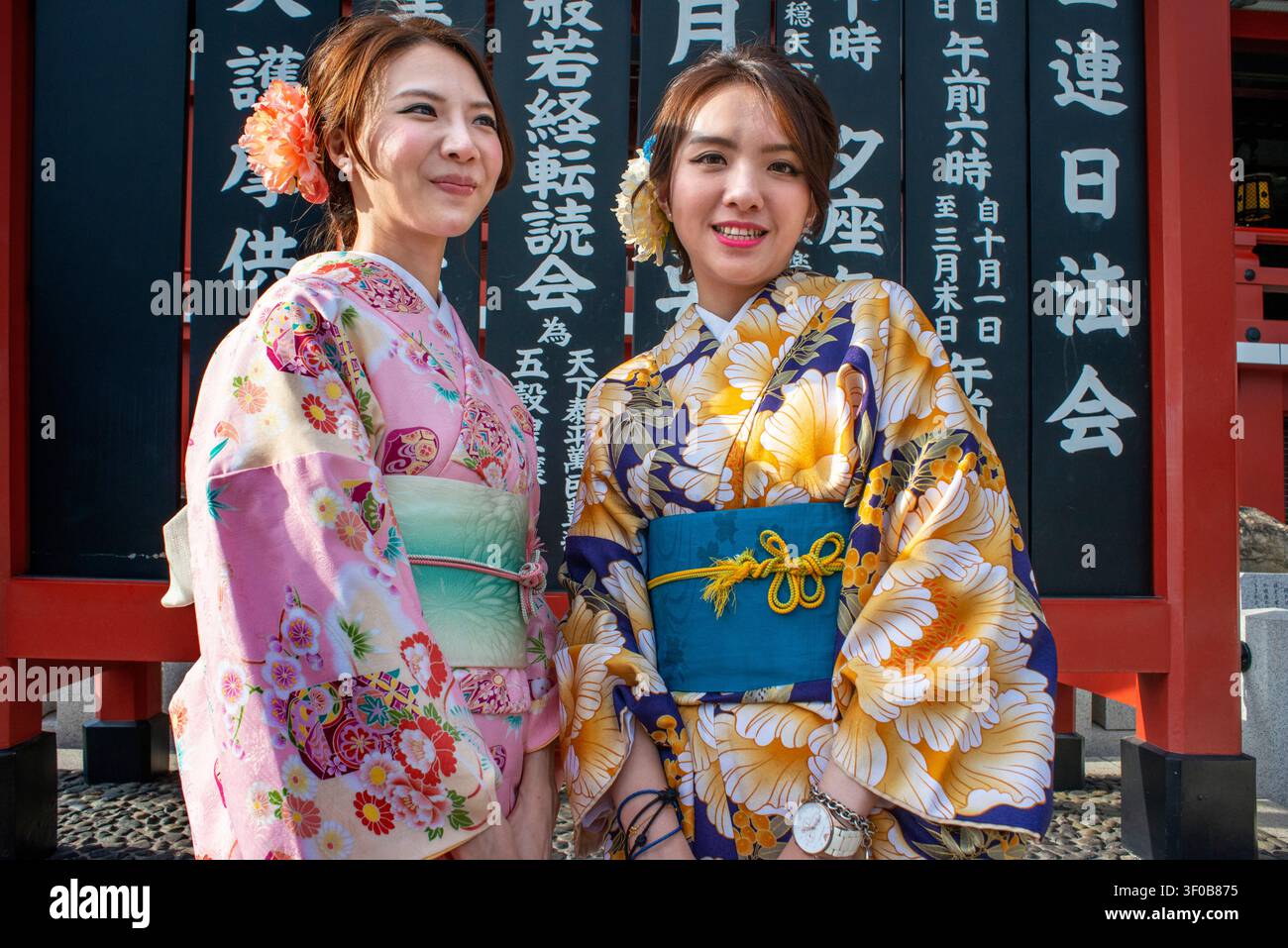 Ragazze turiste in colorati kimoni posano per foto all'iconico portale Kaminarimon ad Asakusa, Tokyo, Giappone. L'immagine cattura l'atmosfera vivace Foto Stock