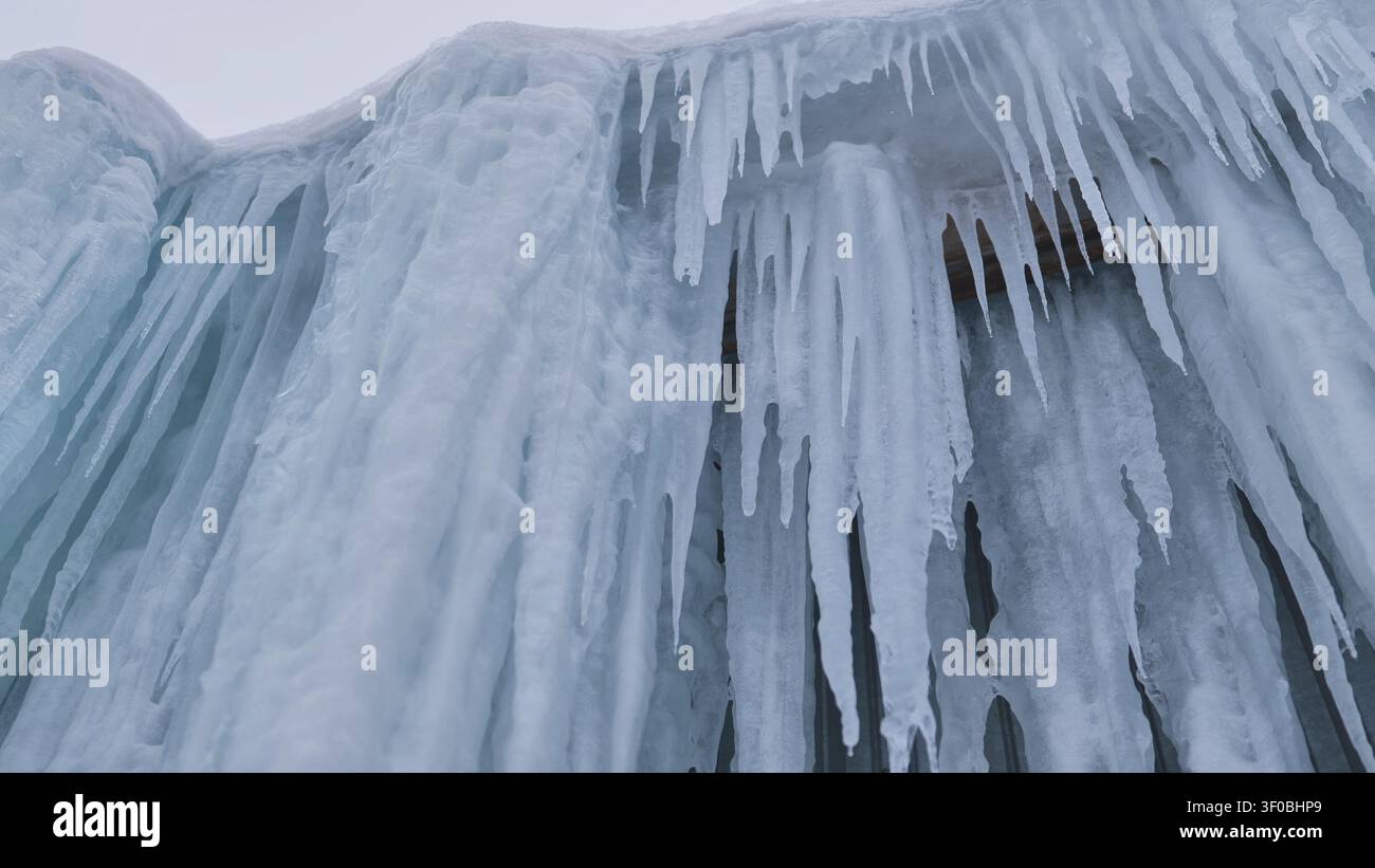 Ghiaccioli appesi a un muro di ghiaccio congelato, creando una fredda scena naturale invernale Foto Stock