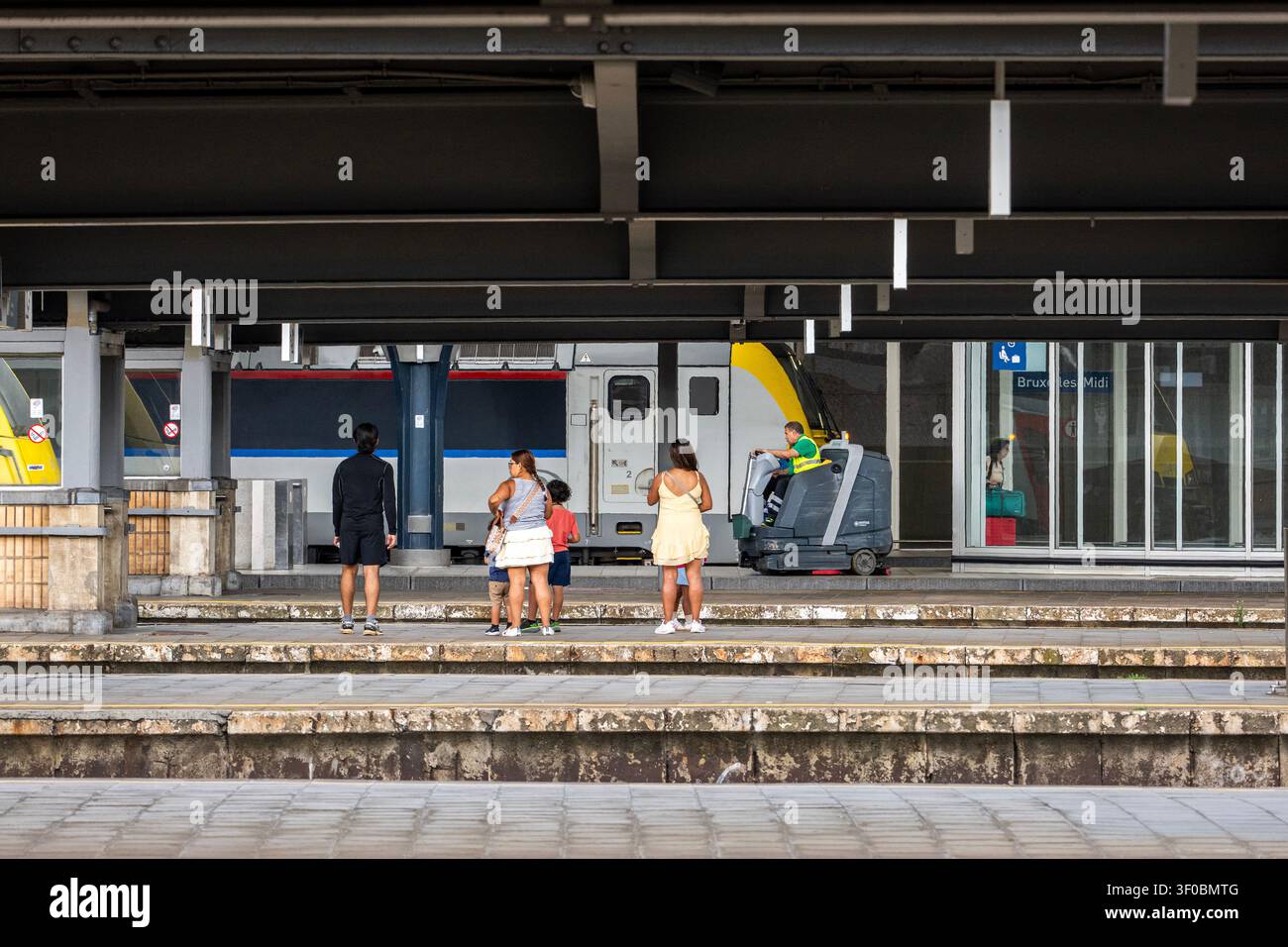 Passeggeri in attesa del loro treno mentre il binario viene pulito Foto Stock