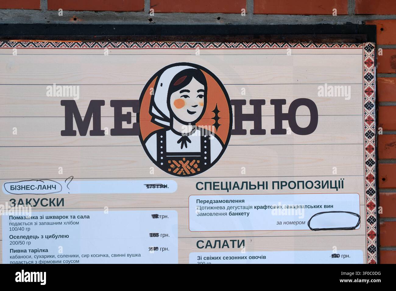 Kyiv, Ucraina - 7 luglio 2026: Tabella del menu di un ristorante con branding ucraino tradizionale e logo femminile illustrato esposto in un esercizio gastronomico Foto Stock