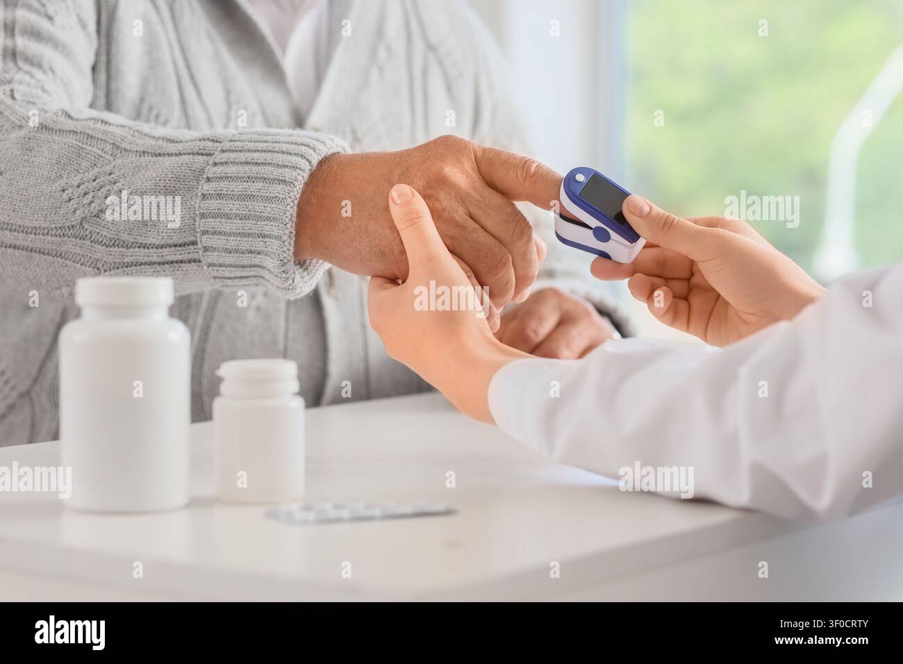 Operatore sanitario che controlla il livello di ossigeno di mans anziani con pulsossimetro Foto Stock