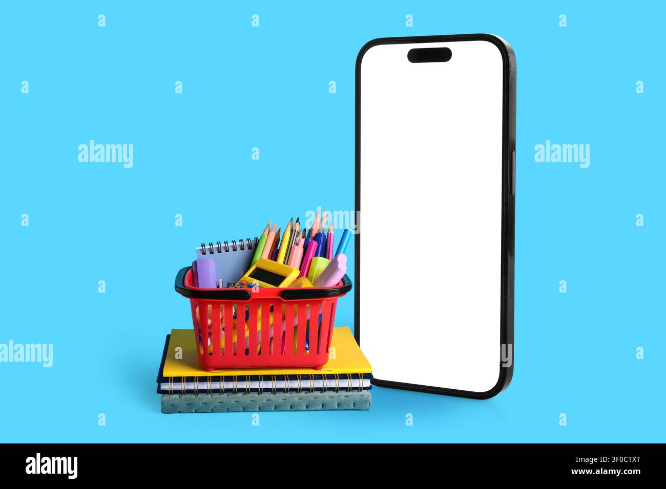 Smartphone con schermo vuoto e cestino dei materiali scolastici sui notebook Foto Stock