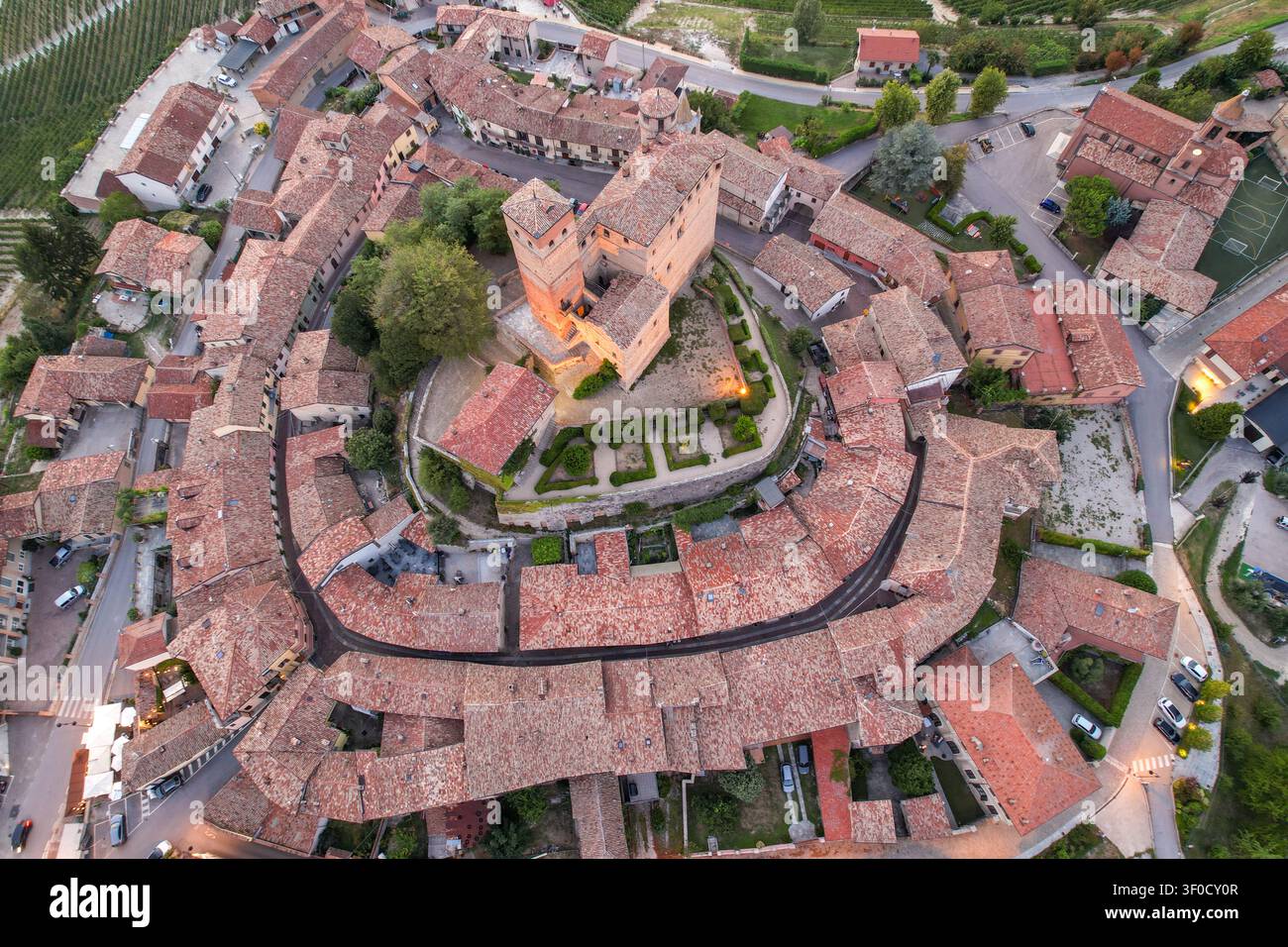 Vista aerea del castello medievale di Serralunga d'Alba circondato da storici tetti in terracotta e lussureggianti vigneti nelle dolci colline di Serralunga Foto Stock