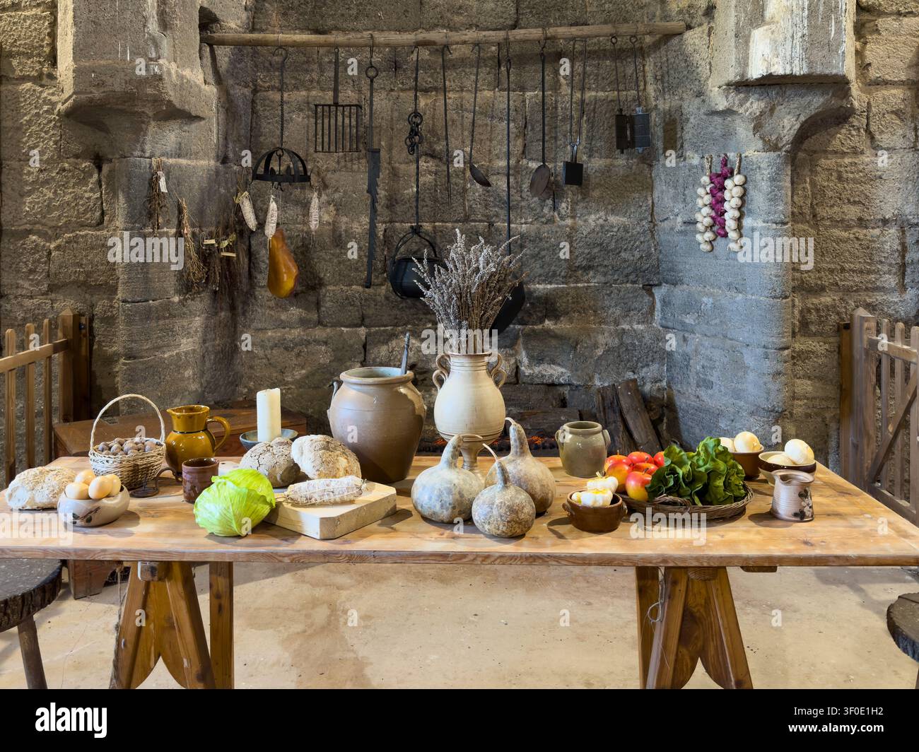 Tavolo da cucina medievale rustico con pane fresco, verdure e utensili da cucina vintage - Immagine stock catturata con smartphone