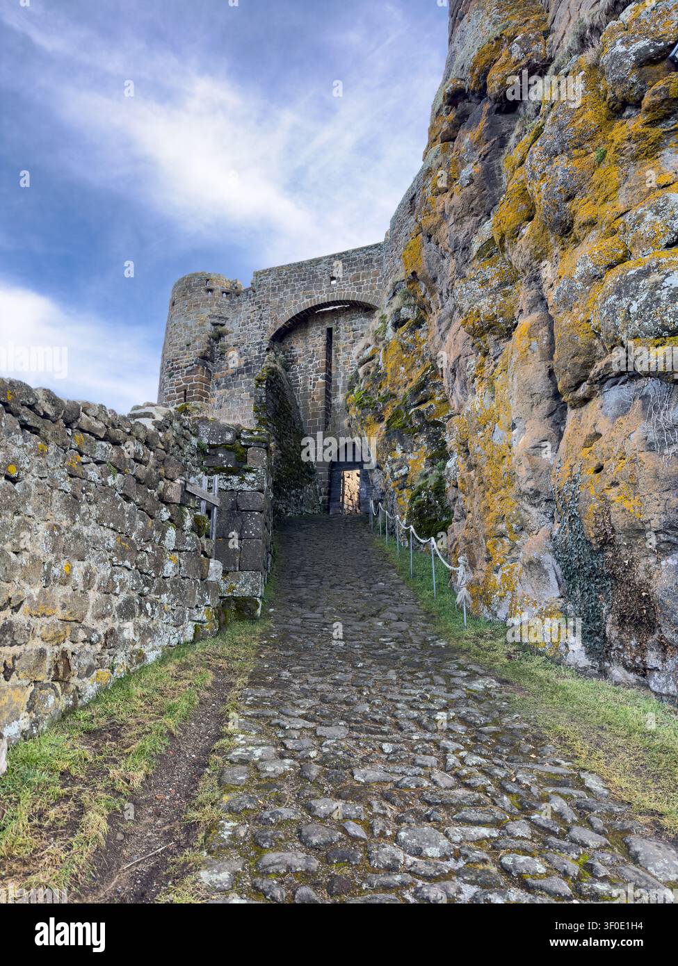 Antico sentiero di ciottoli che conduce a un cancello d'ingresso ad arco di un castello medievale - Immagine stock catturata con smartphone