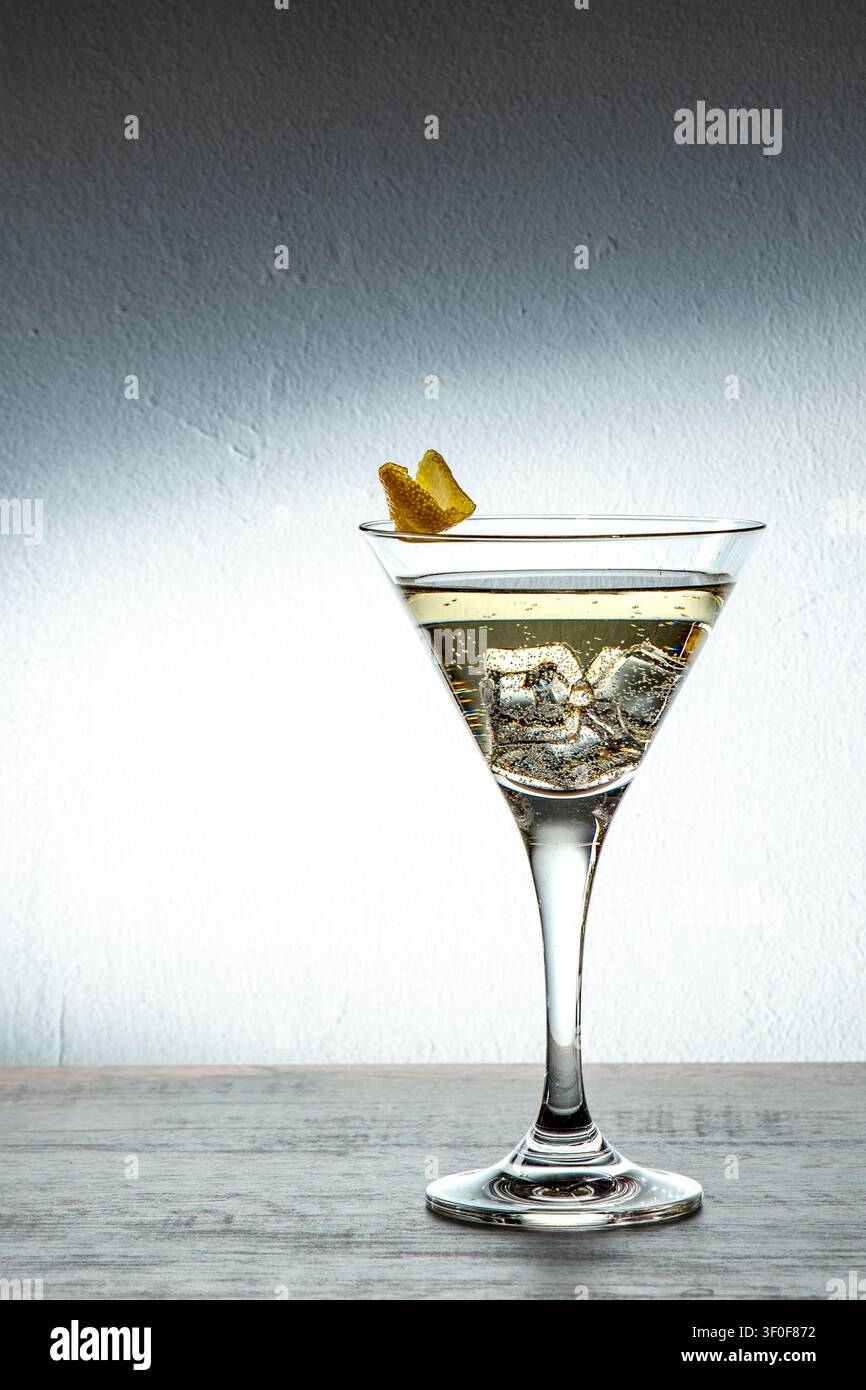 Un drink di San Valentino, martini dorato per celebrare l'amore e il tempo libero. Buccia di limone gialla come guarnizione. Foto Stock