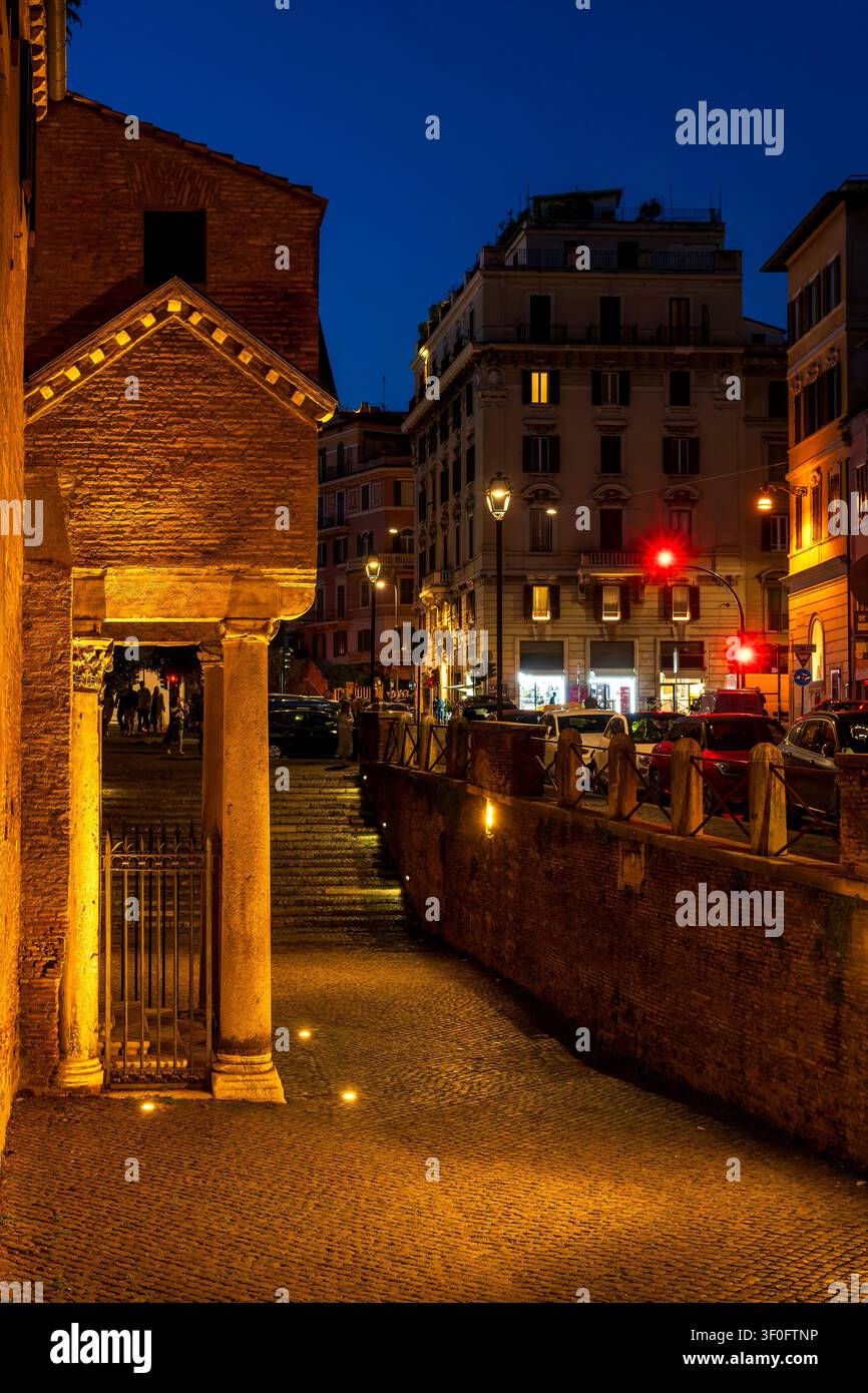 Vista notturna del portico d'ingresso del chiostro di San Clemente con scena illuminata della strada Via Labicana sullo sfondo. Roma, Italia. Foto Stock