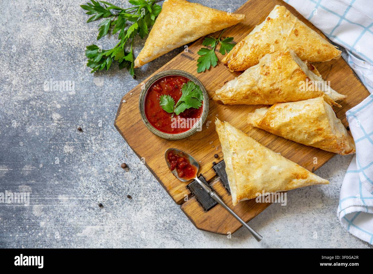 Cibo asiatico tradizionale. Samsa (samosa) vegetariana ripiena di patate con salsa di pomodoro su una superficie di pietra. Colazione sana, spuntino. Vista piatta dall'alto Foto Stock