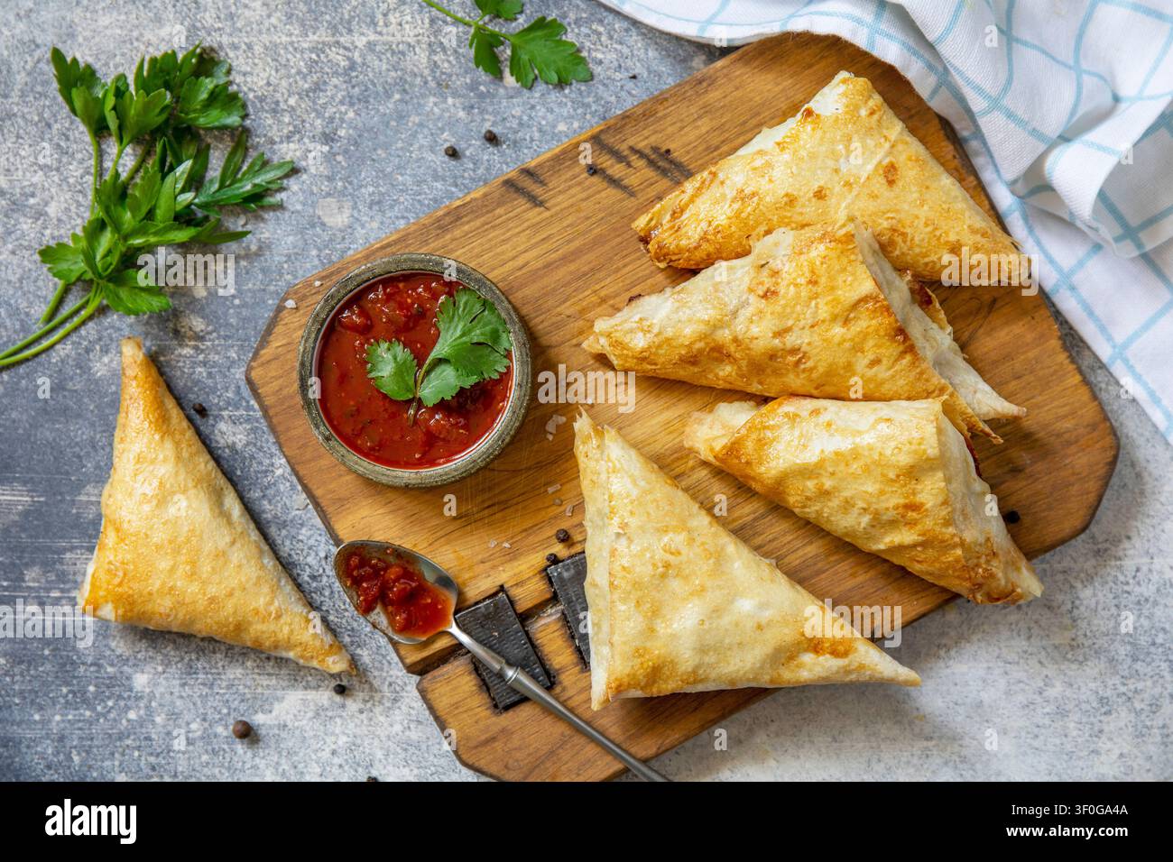 Cibo asiatico tradizionale. Samsa (samosa) vegetariana ripiena di patate con salsa di pomodoro su una superficie di pietra. Colazione sana, spuntino. Vista piatta dall'alto Foto Stock