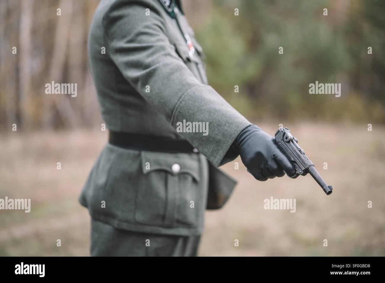 Prima pagina di un ufficiale tedesco che mira una pistola durante una rievocazione storica della Seconda Guerra Mondiale. Concetto di esecuzioni naziste, crimini di guerra, Olocausto, genocidio Foto Stock