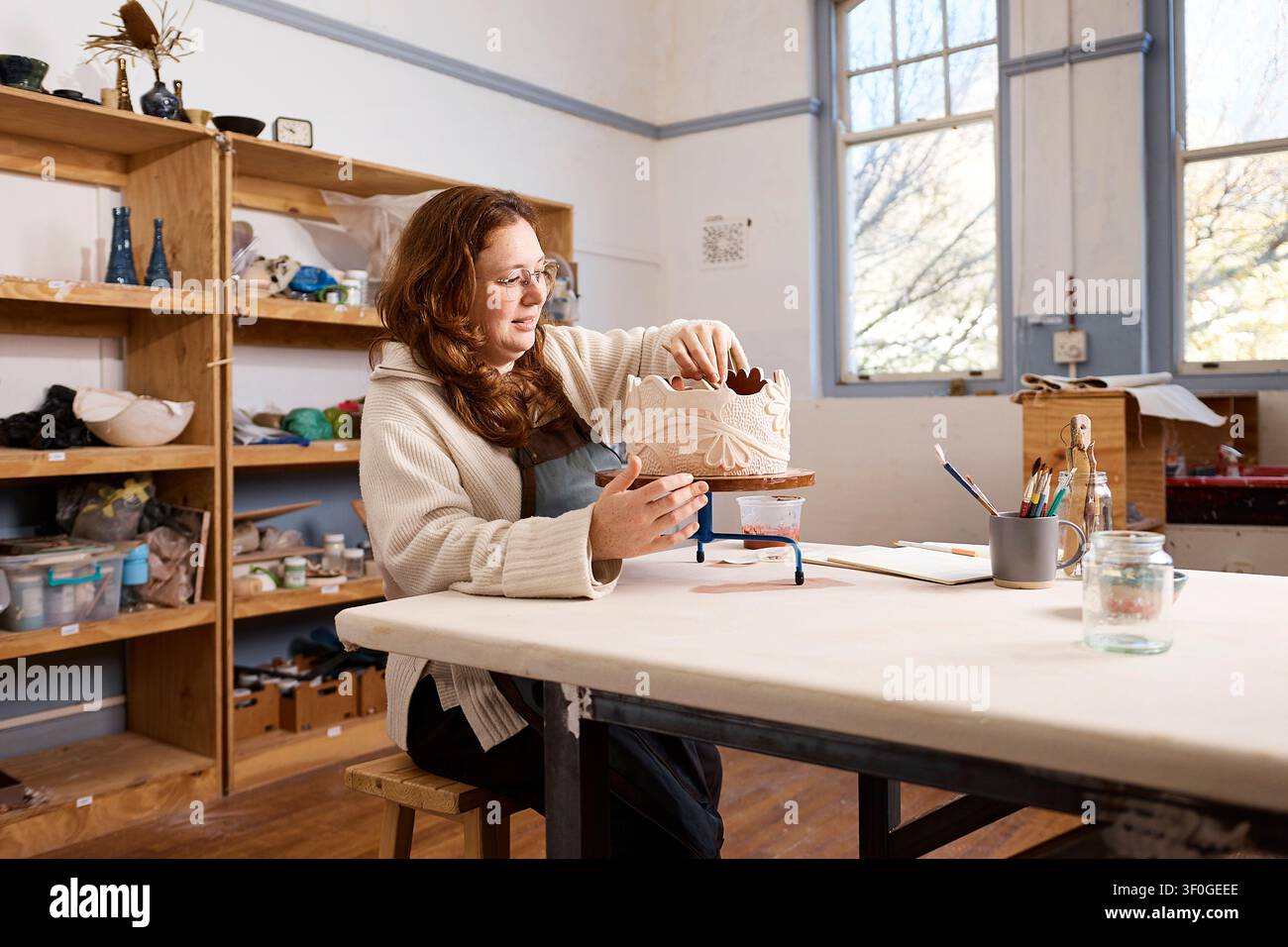 Artista ceramista nel suo studio, che crea a mano una ciotola in ceramica decorativa – Proprietaria di una piccola impresa al lavoro Foto Stock