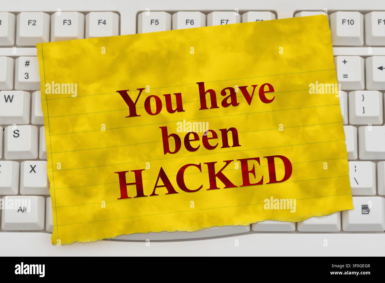 Sei stato hackerato testo su una carta a righe gialla su una tastiera di computer bianca per la sicurezza informatica e i ransomware Foto Stock