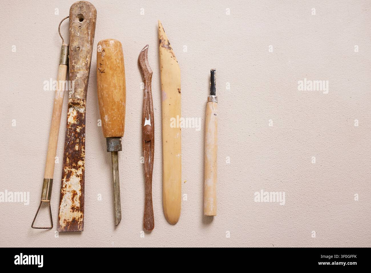 Strumenti per la ceramica e implementi per la modellazione dell'argilla disposti in un banco di lavoro di uno studio di ceramica Foto Stock
