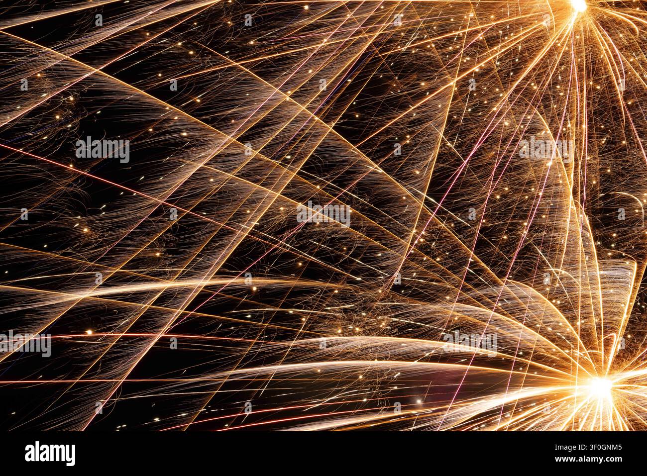 Rete astratta di tracce luminose dorate dense e brillanti che si intersecano su uno sfondo nero, create da un'esposizione lunga di fuochi d'artificio. Foto Stock