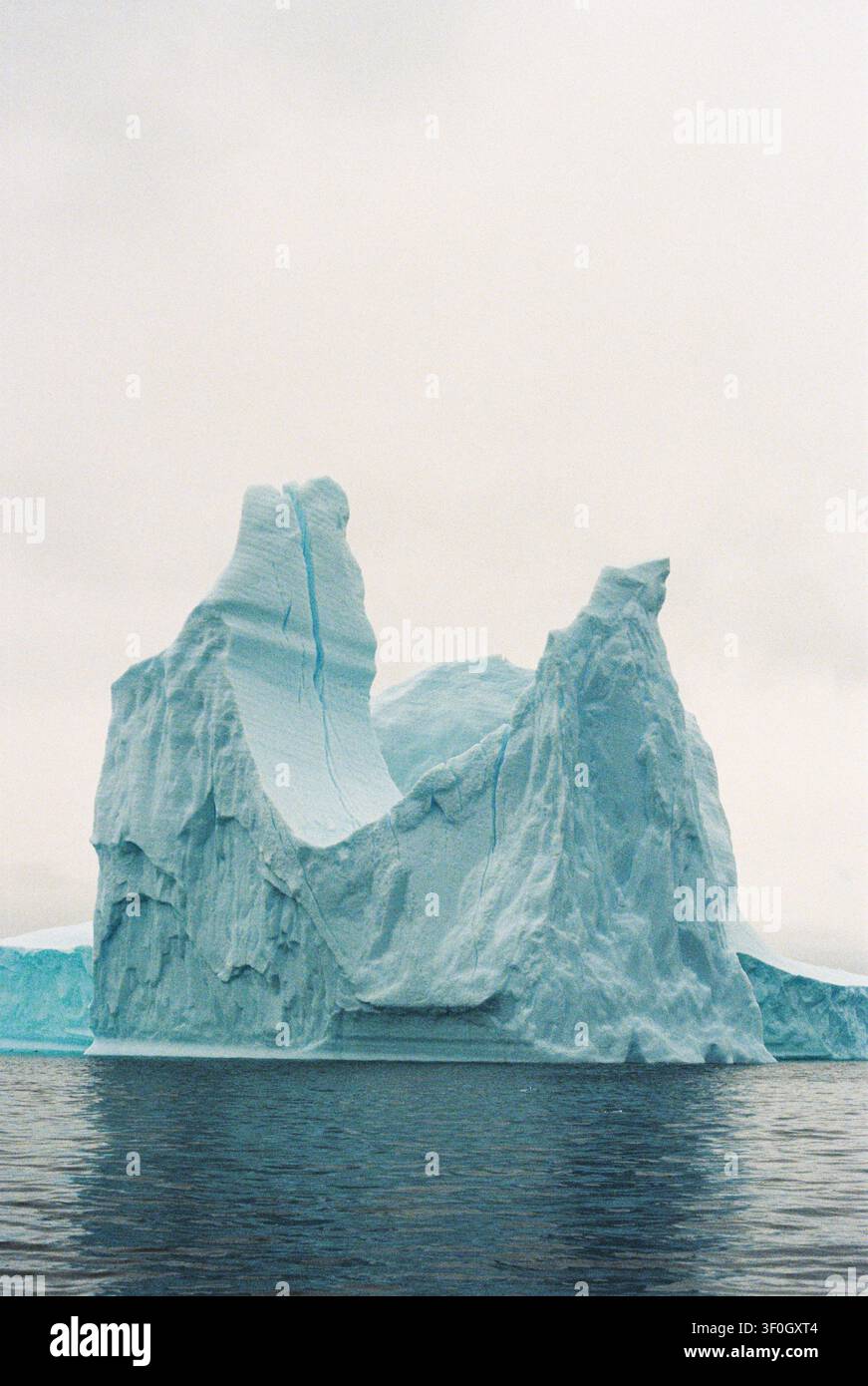 Maestoso iceberg blu che galleggia nelle acque fredde dell'oceano antartico, su pellicola. Foto Stock