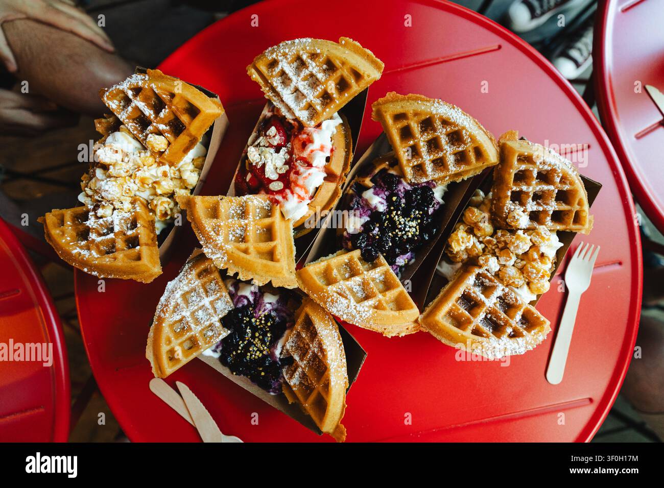 Waffle gourmet da dessert con assortimento di guarnizioni su tavolo rosso Foto Stock