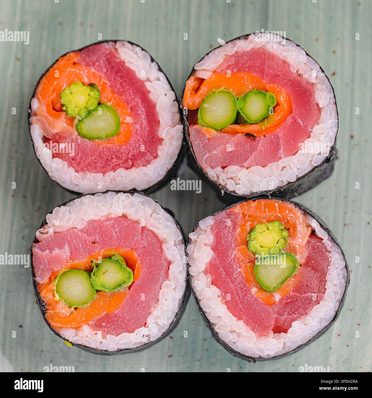 Una foto che mostra quattro rotoli di sushi con fette di cetriolo fresco disposte sopra. Foto Stock