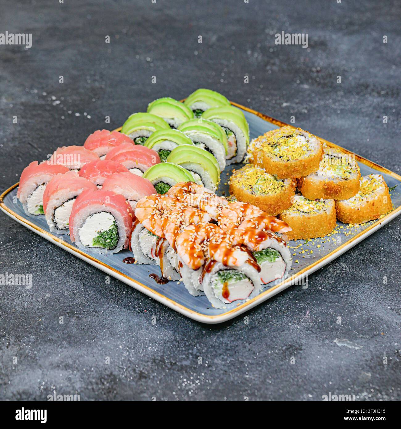 Un piatto pieno di una varietà di sushi e roll, ordinatamente disposti su un tavolo. Foto Stock