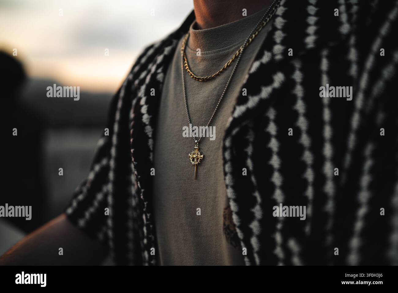 Prima vista di un uomo che indossa collane d'oro e d'argento sopra una camicia elegante Foto Stock
