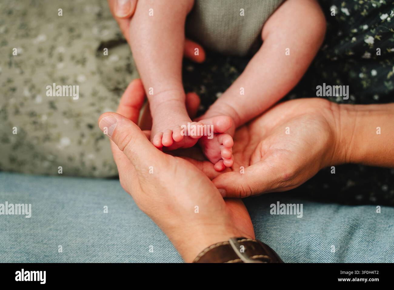 Padre che tiene i piccoli piedi di un neonato nelle sue mani Foto Stock