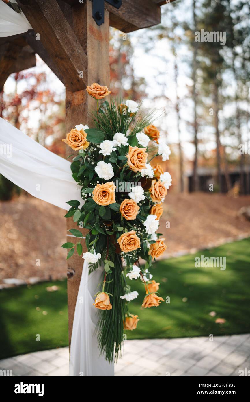 Elegante composizione floreale arancione e bianca su arco di legno rustico Foto Stock