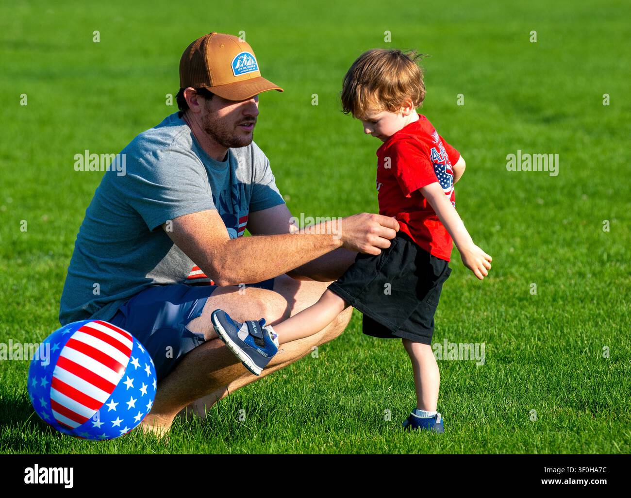 Un padre dà una mano al figlio mentre giocano a calcio nel parco cittadino di Montrose, Colorado. Foto Stock