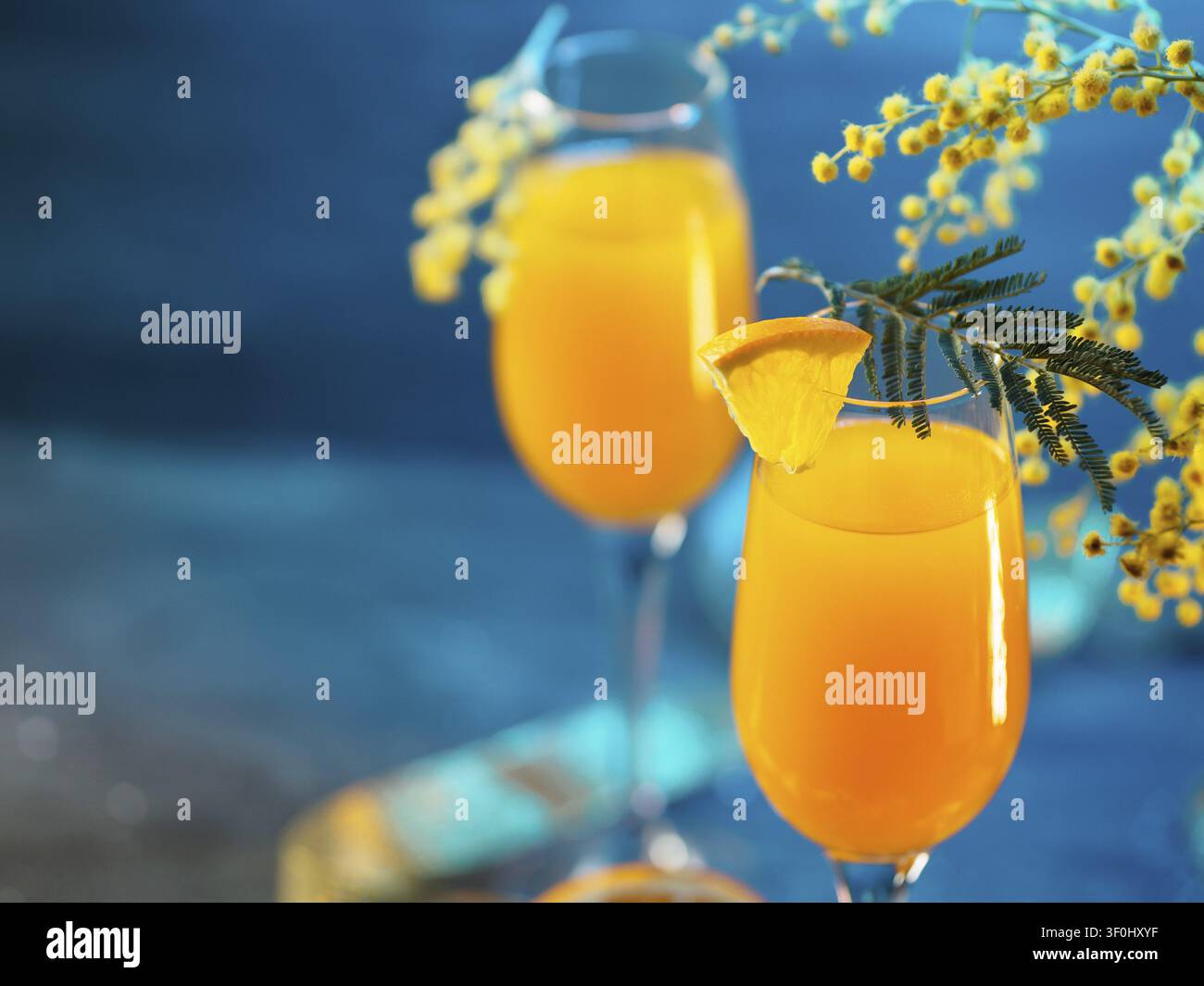 Cocktail mimosa e fiori su uno sfondo blu Foto Stock