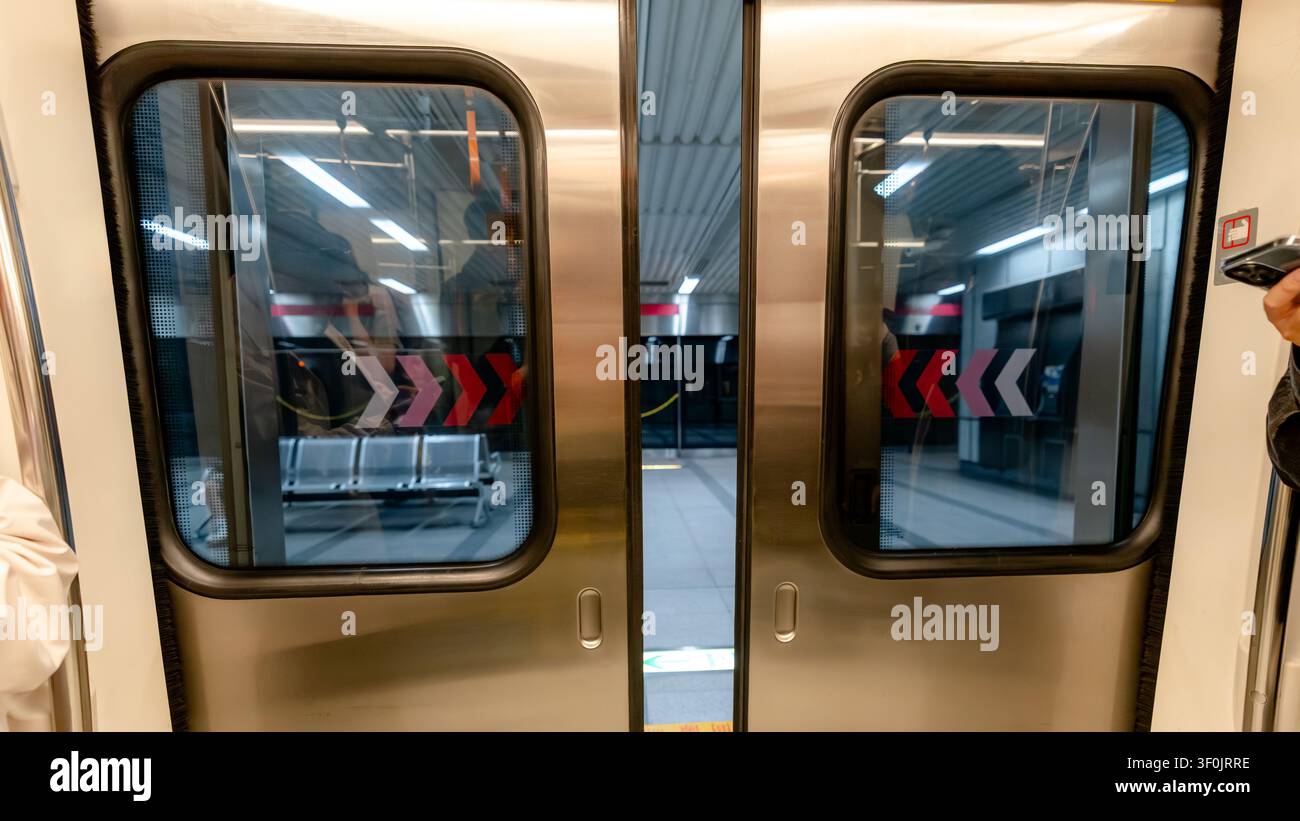 Prima di una porta del treno della metropolitana di Kaohsiung su un binario della stazione sotterranea a Taiwan, che mostra riflessi moderni degli interni della metropolitana, segnalazioni di sicurezza e Foto Stock