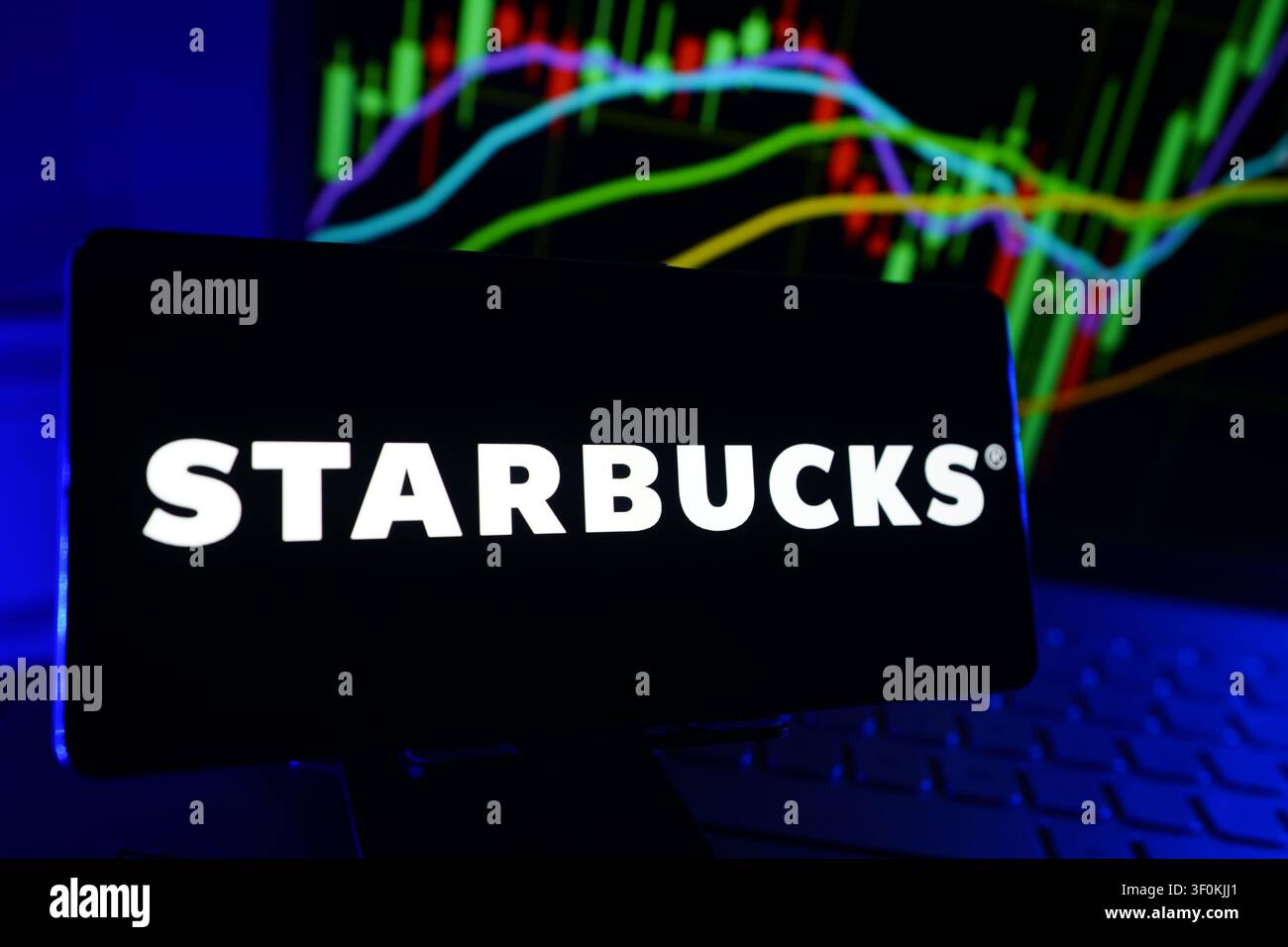 Logo della catena di caffetterie Starbucks e dell'azienda globale di vendita al dettaglio di bevande su display di smartphone con grafico delle prestazioni del mercato azionario Foto Stock