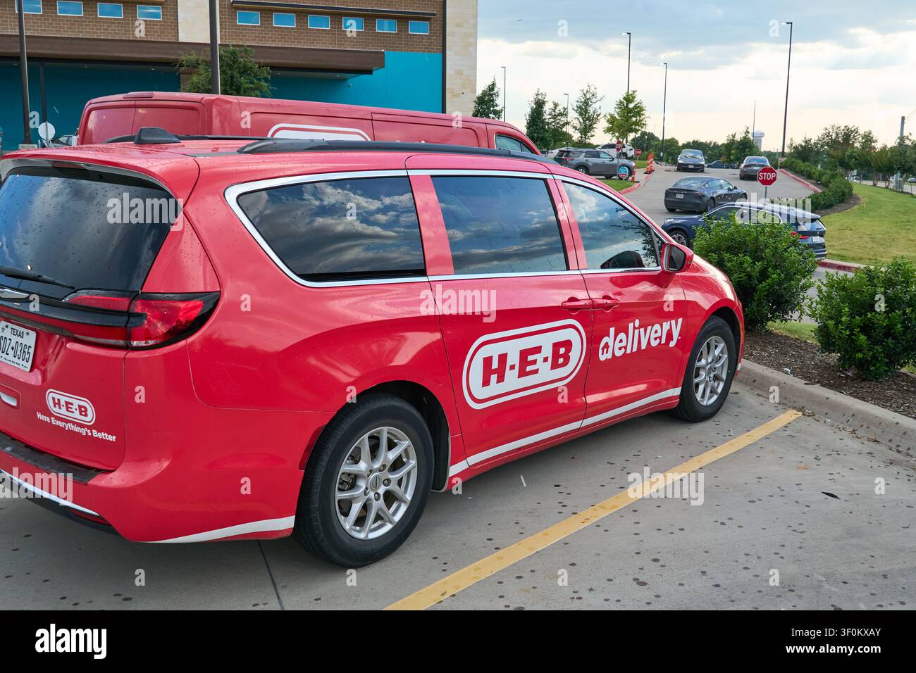 PLANO, TX, USA - 06 LUGLIO 2026: Un minivan di consegna rosso H-E-B è parcheggiato in un parcheggio suburbano, mostrando il logo e lo slogan del marchio. H-E-B, un pop Foto Stock
