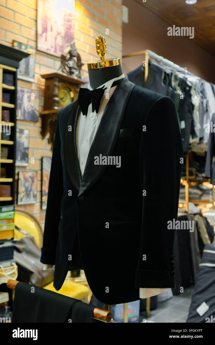 Smoking su misura per uomo di lusso premium e completo a tre pezzi su misura esposti su manichini all'interno di un atelier-boutique di alta moda. Foto Stock