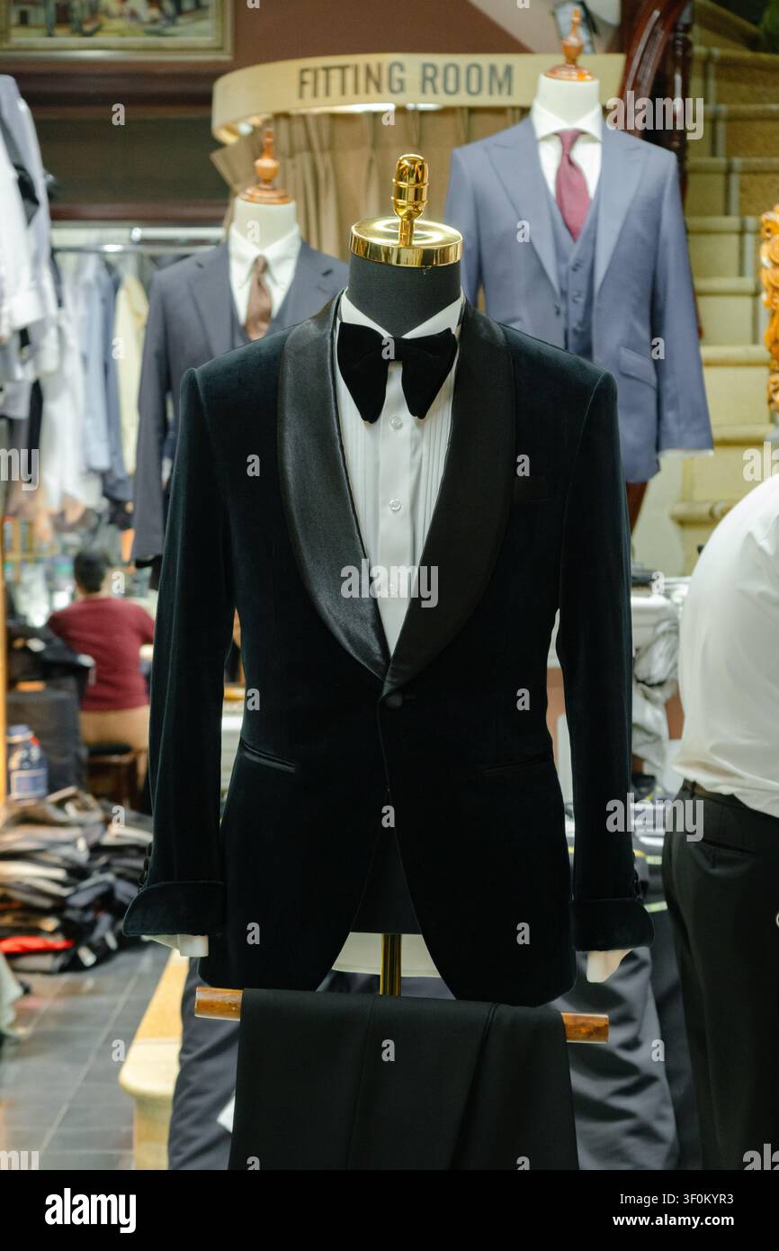 Smoking su misura per uomo di lusso premium e completo a tre pezzi su misura esposti su manichini all'interno di un atelier-boutique di alta moda. Foto Stock