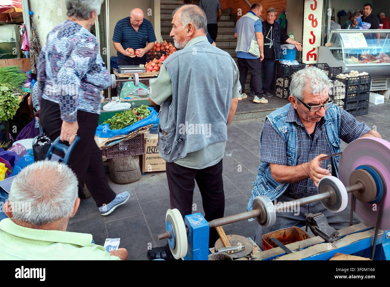 Un artigiano affilatore al vivace mercato del Dezerter Bazaar a Tbilisi, Georgia, Caucaso, Eurasia, Europa orientale Foto Stock